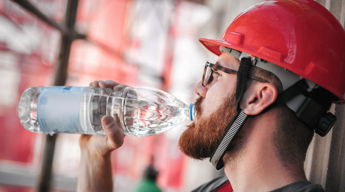 — title missing — Worker in hard hat, sitting and drinking big bottle of water