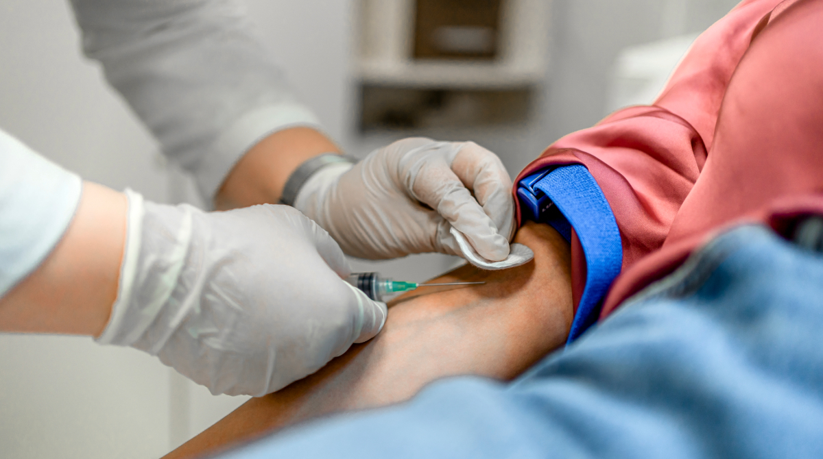 -- title missing -- Manos con guantes extrayendo sangre del brazo de un paciente.