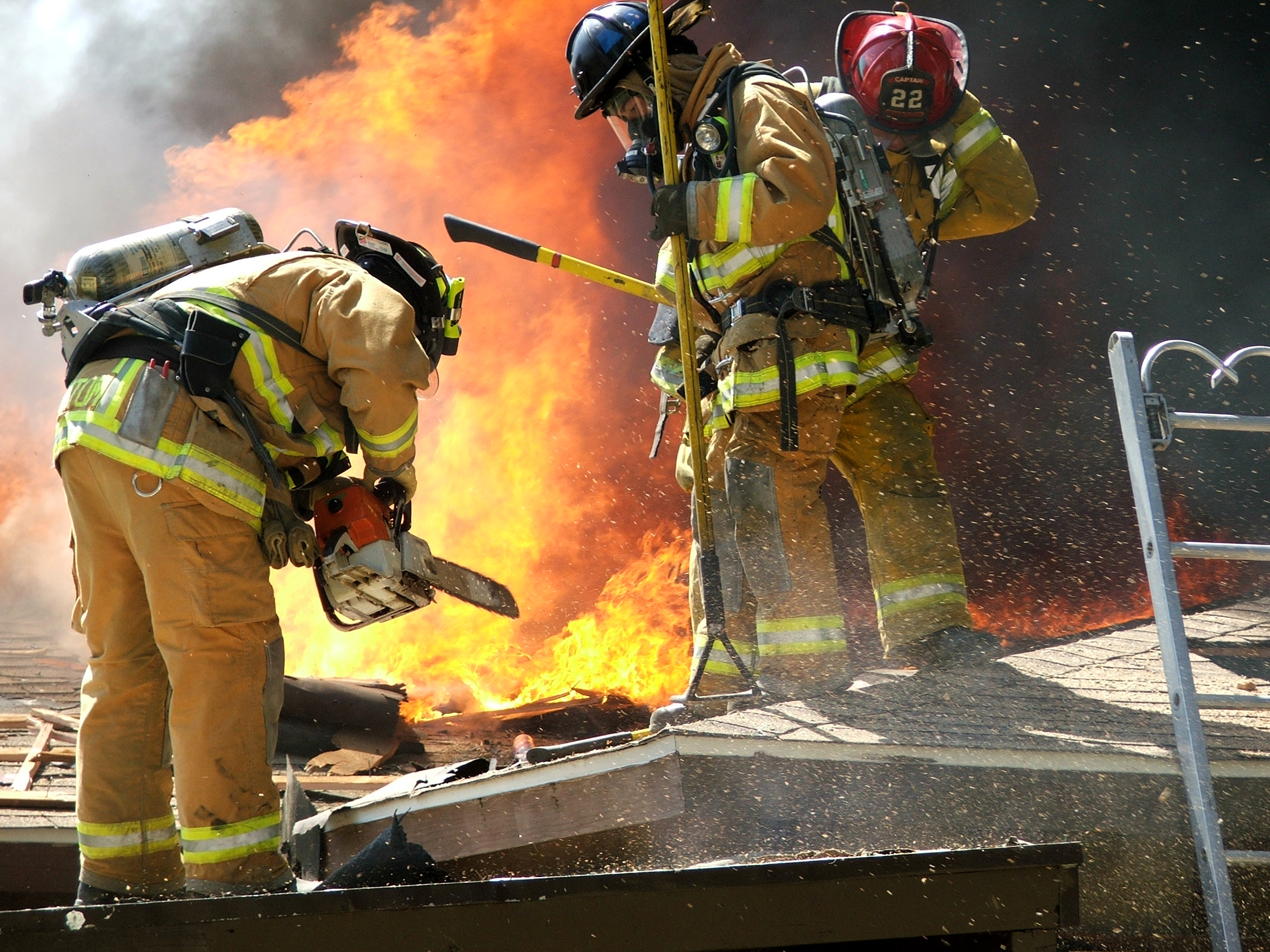 GettyImages157282300.jpg Bomberos usando EPP, llevando equipos, cerca de grandes llamas de fuego