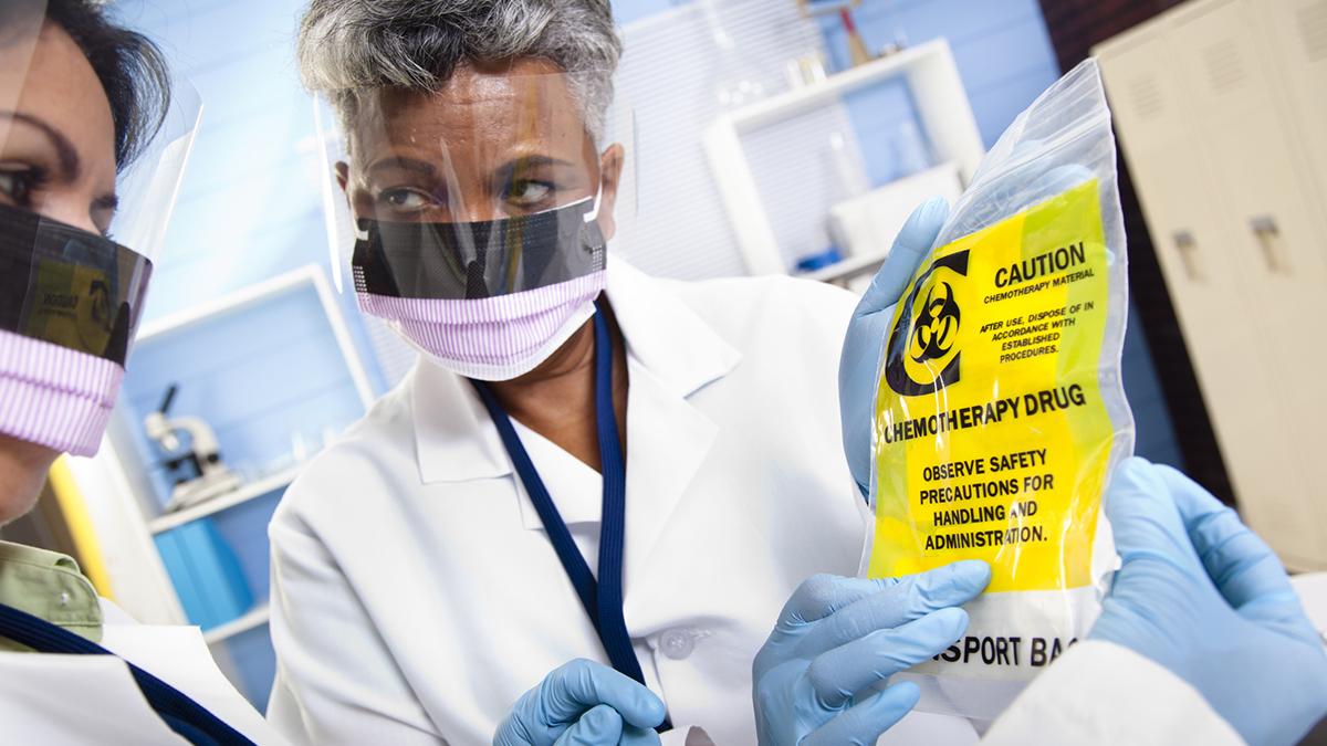 — title missing — Multi-ethnic doctors or scientists discussing medical contents of chemotherapy bag.