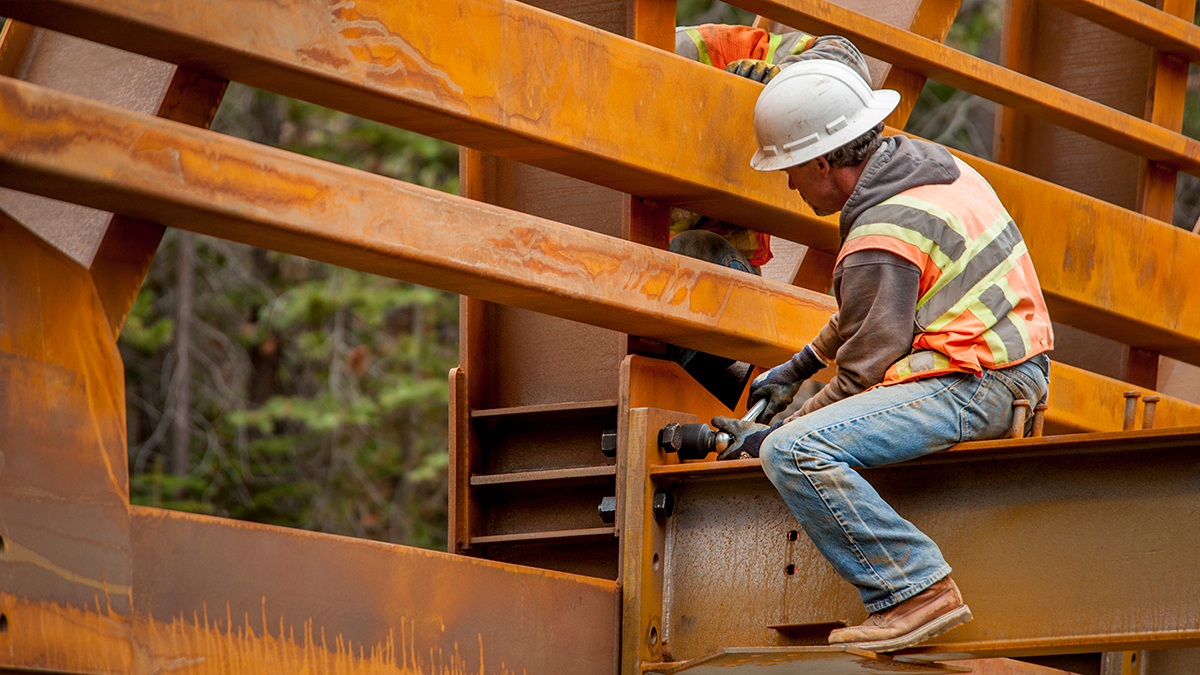 — title missing — Steel workers on a bridge in the woods