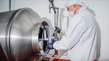 — title missing — Scientist wearing a white lab coat working on a manufacturing tumbler