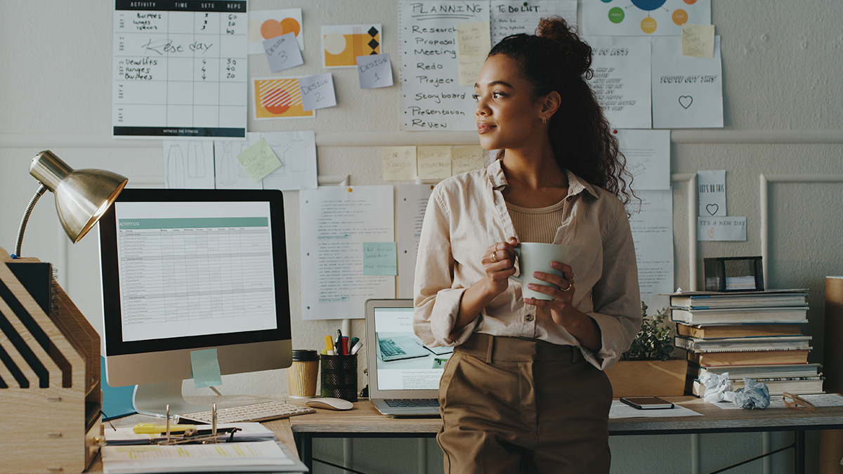 — title missing — Work in office holding a coffee cup looking hopeful