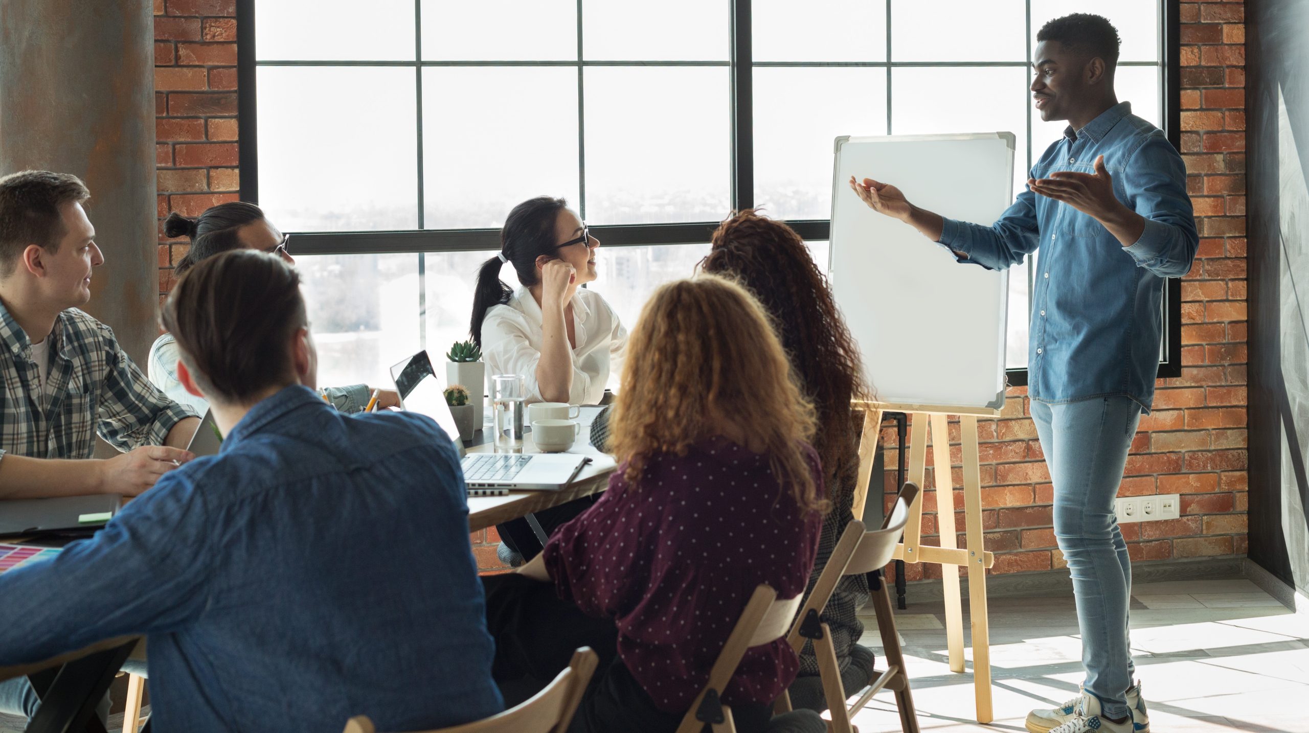 — title missing — Man standing up in front of coworkers giving a presentation
