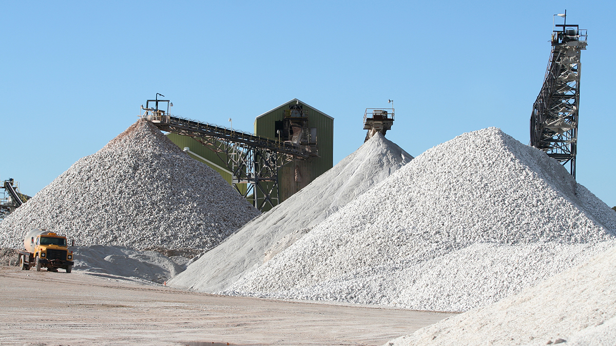 Surface mine with piles of gravel and heavy equipment.