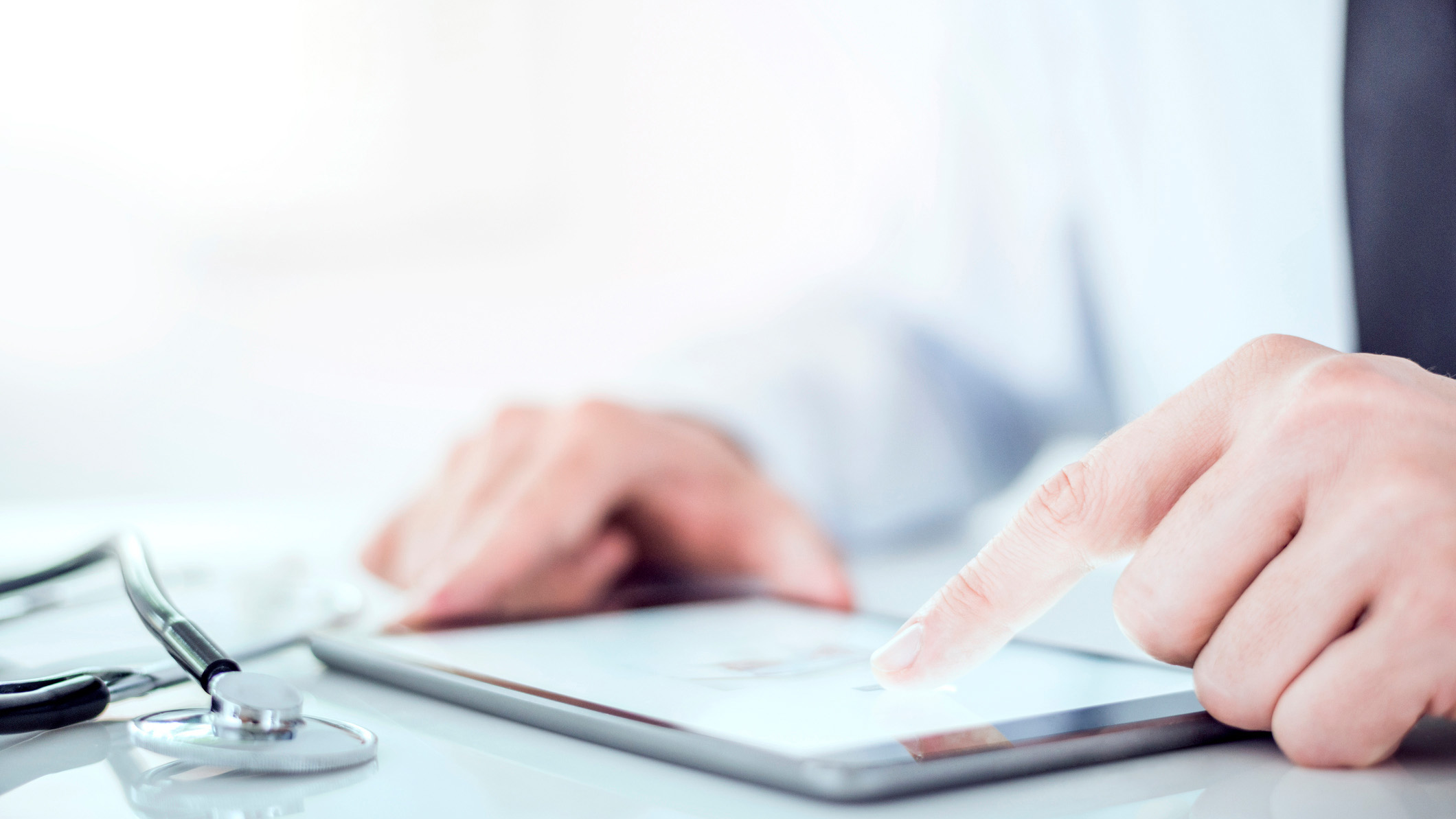 — title missing — Close up of doctor looking at a digital tablet with a stethoscope lying beside the tablet.