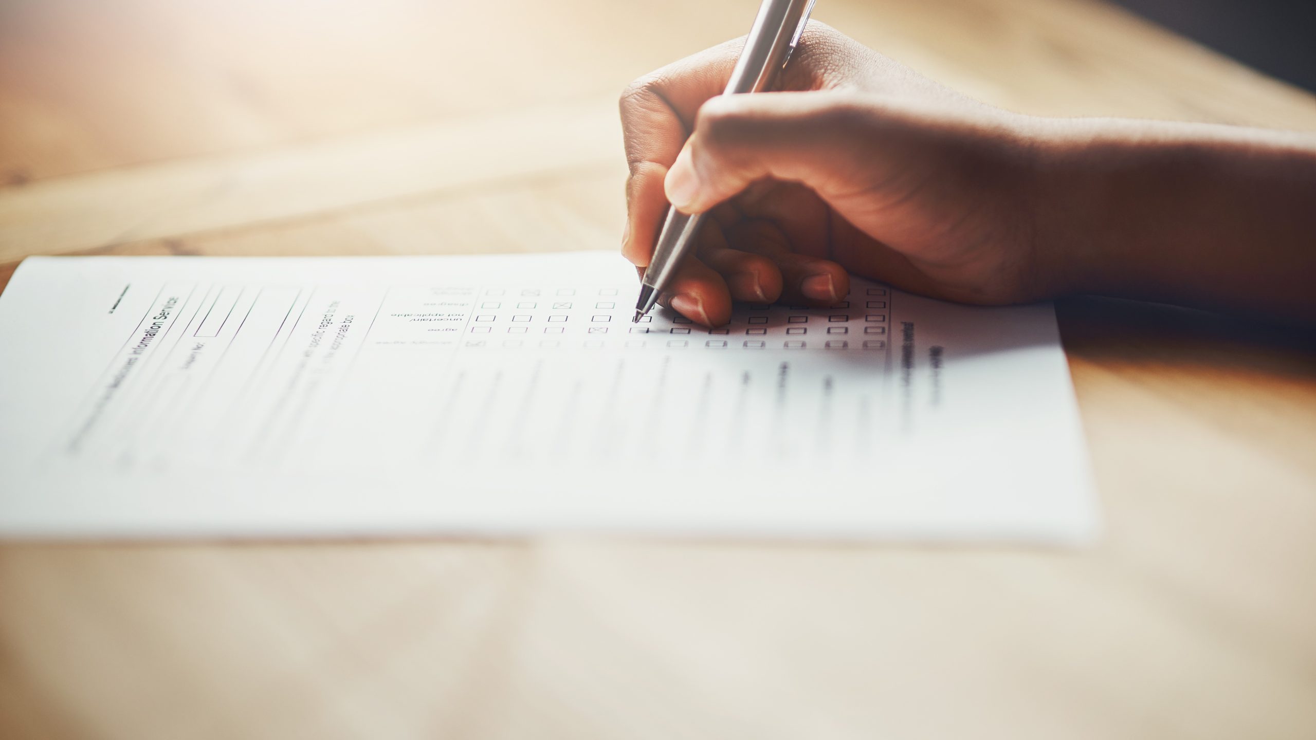 — title missing — Hand with pen filling out a form.