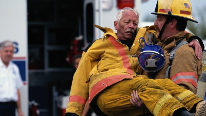 — title missing — A firefighter carries an older firefighter to an ambulance