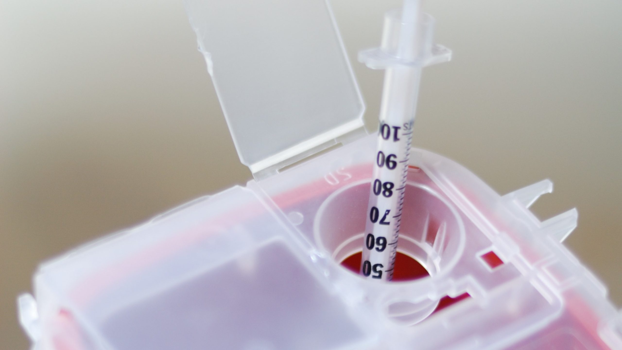 -- title missing -- A needle being placed in a sharps disposal container.