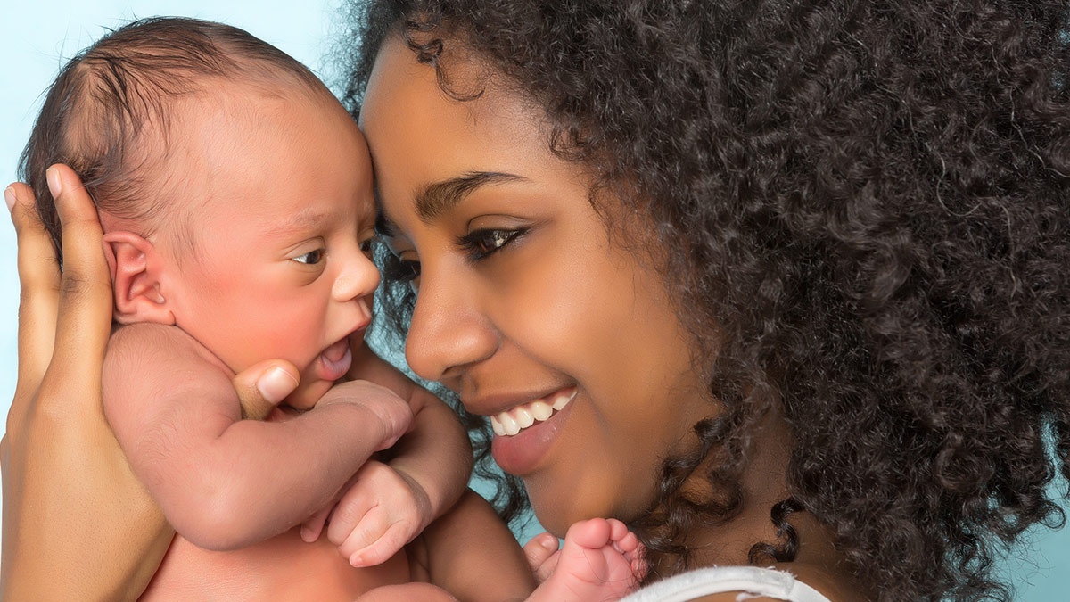 Pregnancy Data - Thumbnail A smiling mother with curly hair lovingly holds her newborn baby, both facing each other closely.