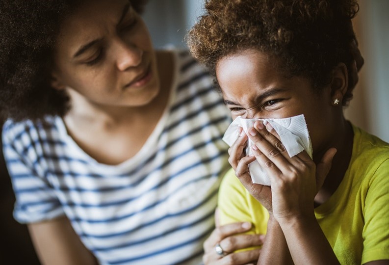 parent and child with enterovirus Parent with sick child blowing their nose.