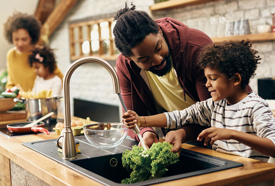 norovirus-home-washing-food.jpg Padre ayuda al hijo a lavar verduras.