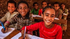 — title missing — Students in classroom taking notes in notebooks.