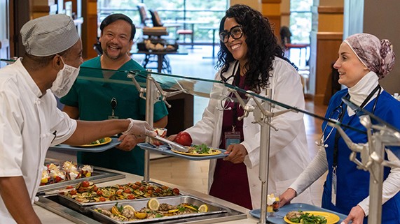 — title missing — Employees getting food in a hospital cafeteria.