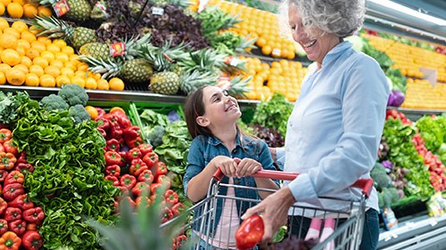 — title missing — Grandmother and child shopping for fruits and vegetables in grocery.