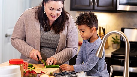 — title missing — Mother and son preparing vegetables in home kitchen.