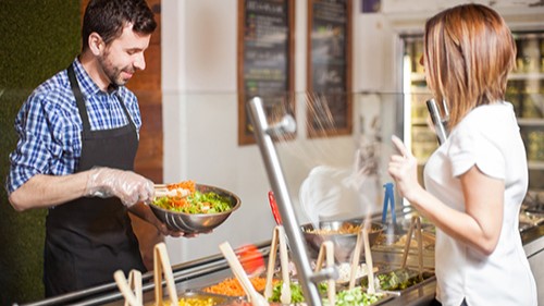 — title missing — A person getting a salad at a worksite cafe.