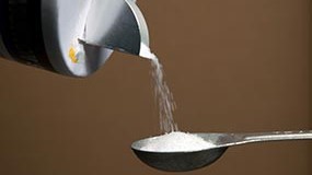— title missing — Closeup photo of salt being poured into a measuring spoon.
