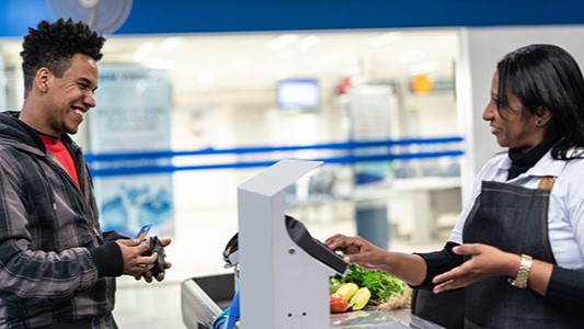 — title missing — Man at grocery store checkout with fruit and vegetables.
