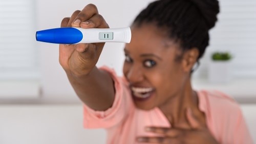 — title missing — Woman looks happy with result of an at-home pregnancy test.