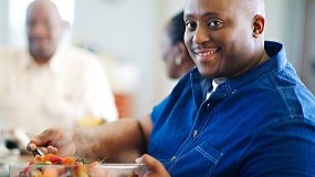 — title missing — Man getting a serving of fruit from a large bowl.