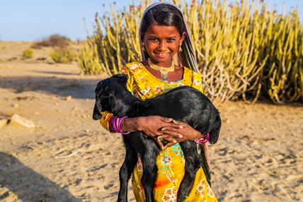 One Health Zoonotic Disease Prioritization A girl smiles at the camera while holding a black baby goat