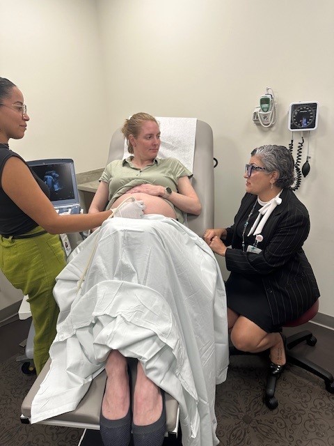 Pregnancy Photo of a pregnant woman in a medical chair speaking to a female doctor as another woman does an ultrasound