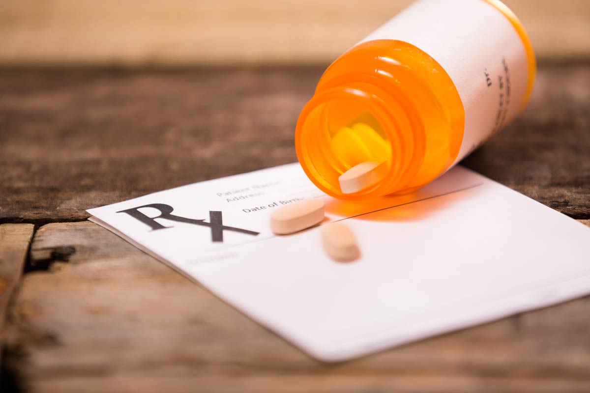 Antiviral pills spilling out of bottle over prescription pad Antiviral pills spilling out of bottle over prescription pad