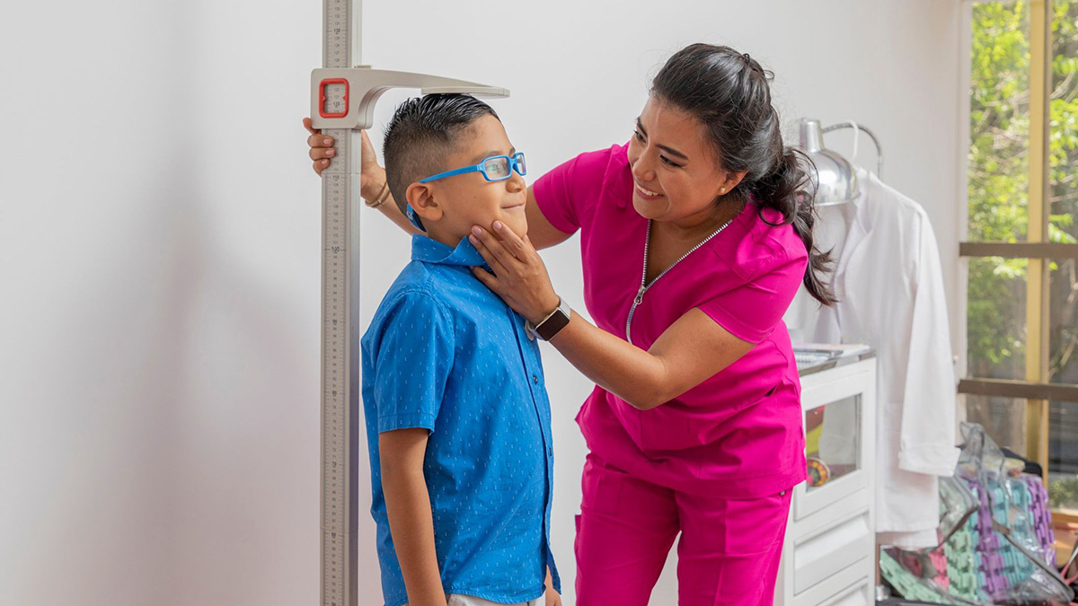 Measuring height Pediatric female doctor holding a child's head while measuring it with a floor ruler
