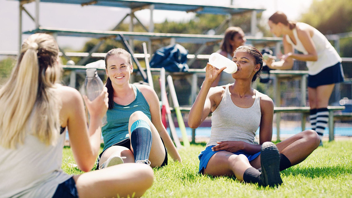 Teens involved in heathy activities Sport, outdoor and women relax with water bottle, hydration and rest, field hockey athlete take training break.