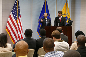 Presentation-Speakers Two men wearing suits standing at a lectern speaking in front of an audience.