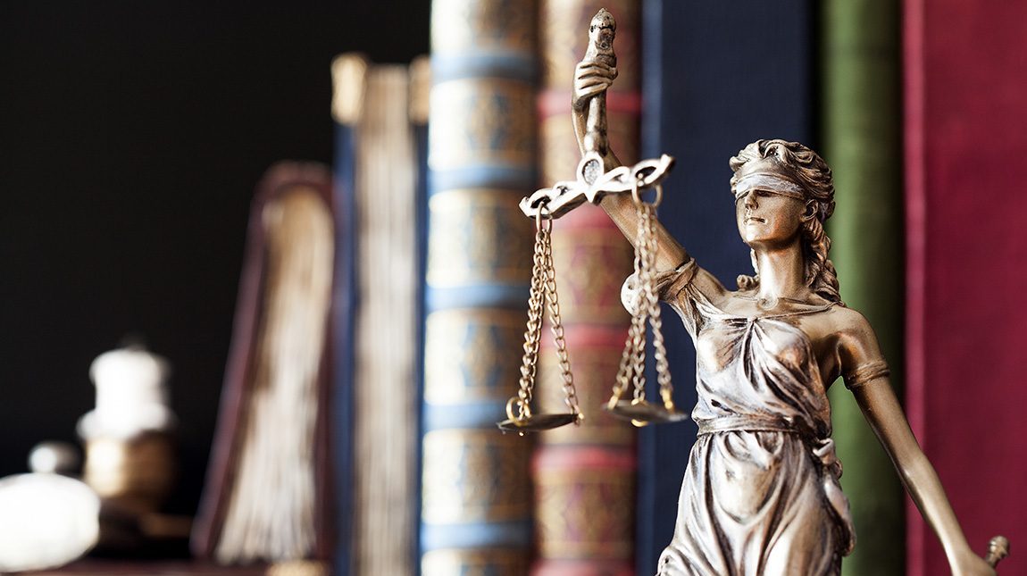 phlp-main Lady justice statue holding scales with books in the background