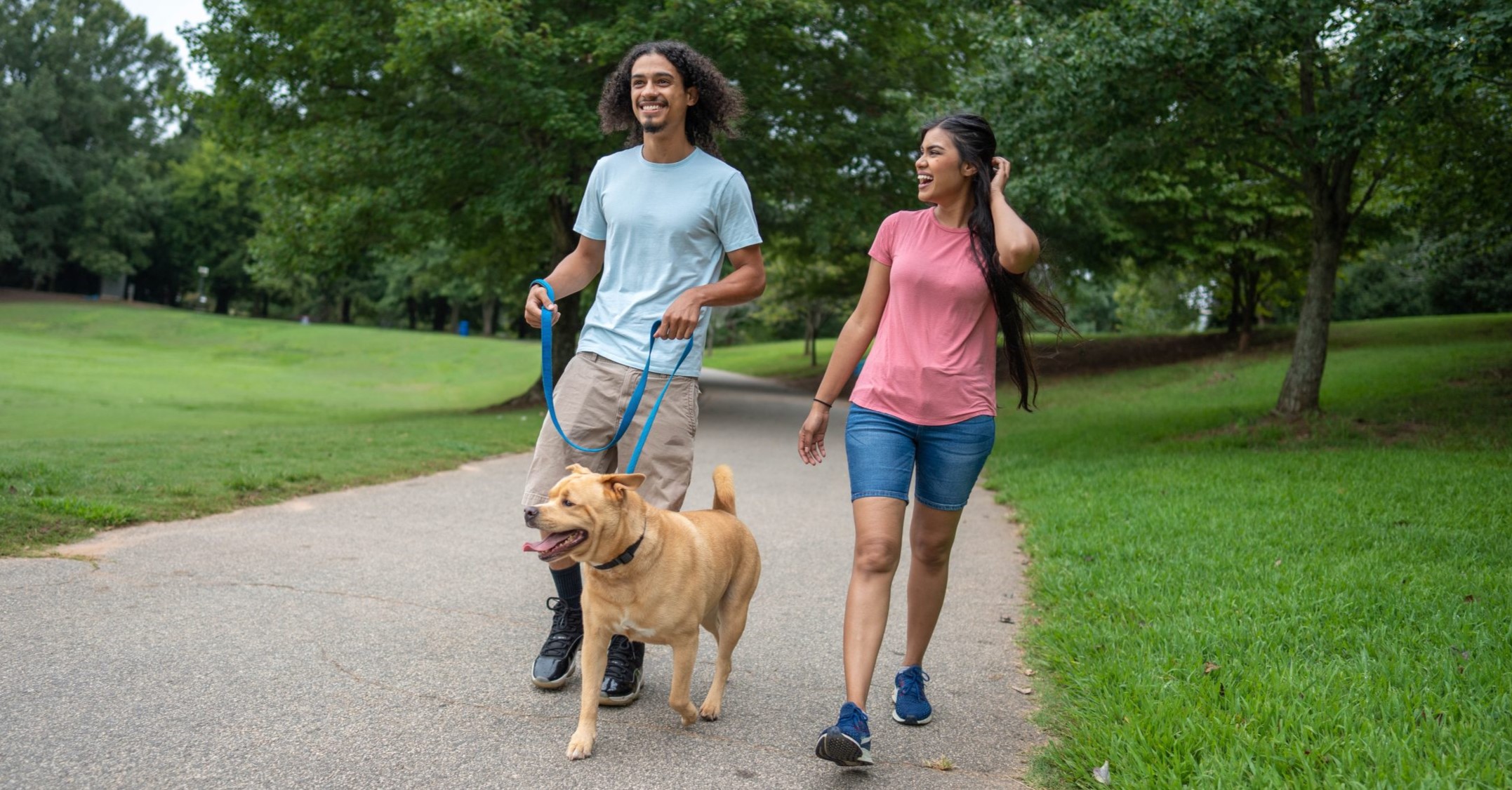 Overcoming barriers to physical activity. Man and woman walking a dog outside.