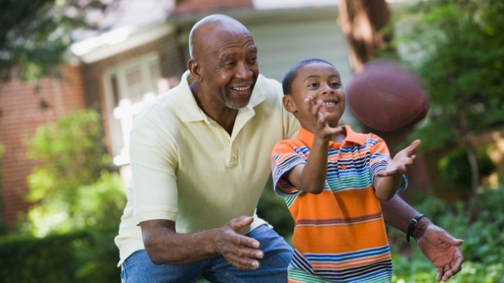 — title missing — Older man playing football with his grandson.