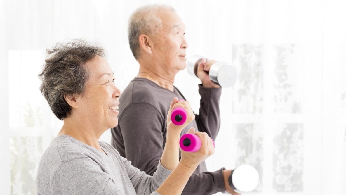 — title missing — Two older adults lifting weights.