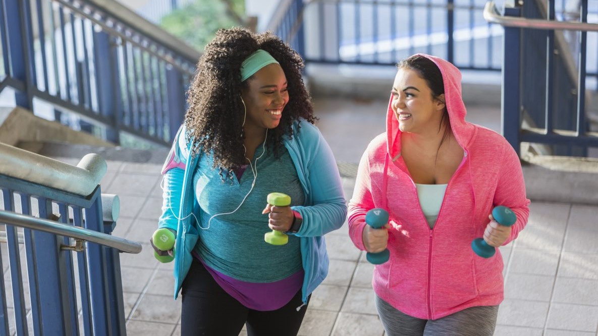 — title missing — Two women walking up stairs and carrying hand weights