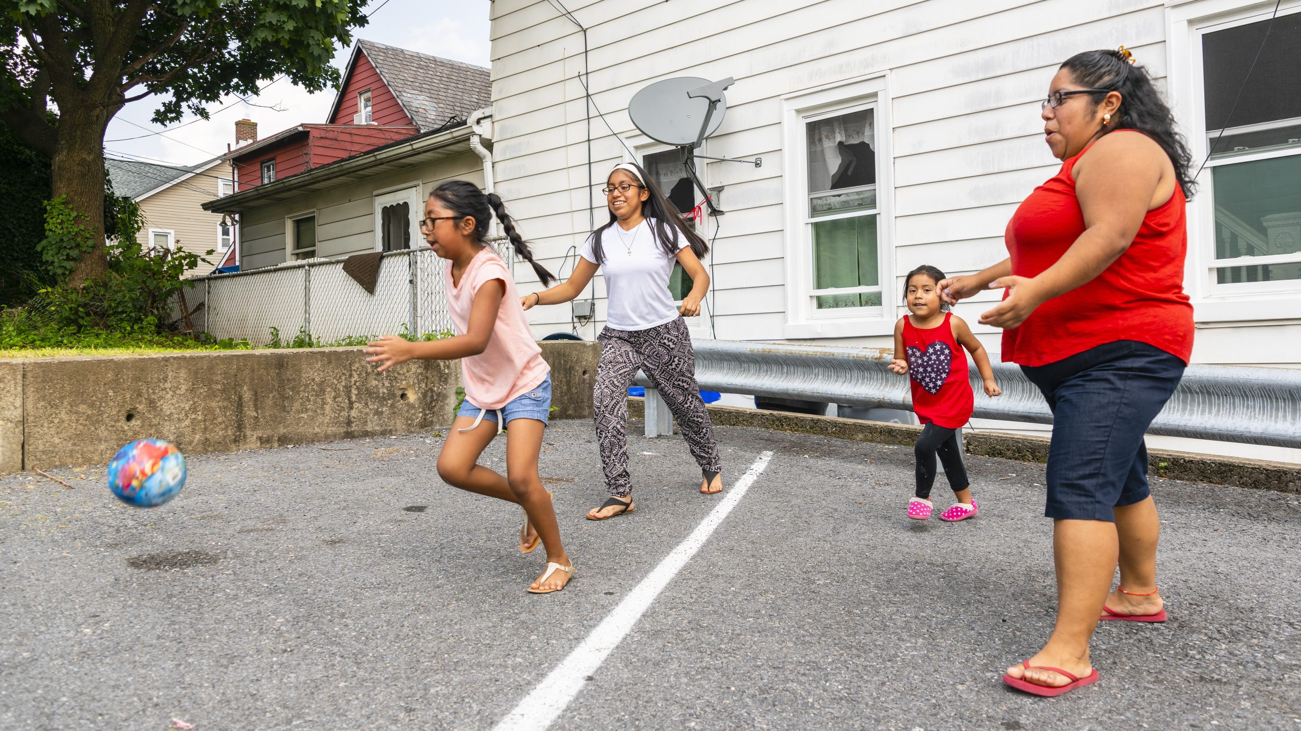 -- title missing -- Family playing ball outside a house.