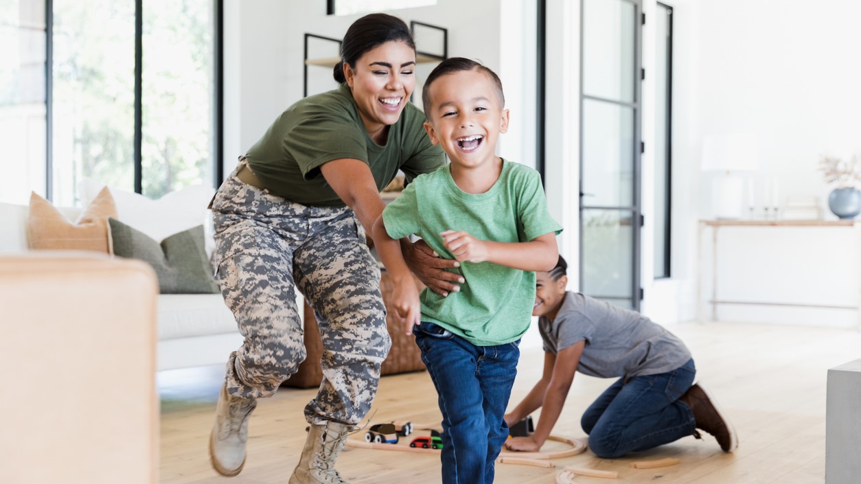 — title missing — A woman in uniform chasing her son around their home.