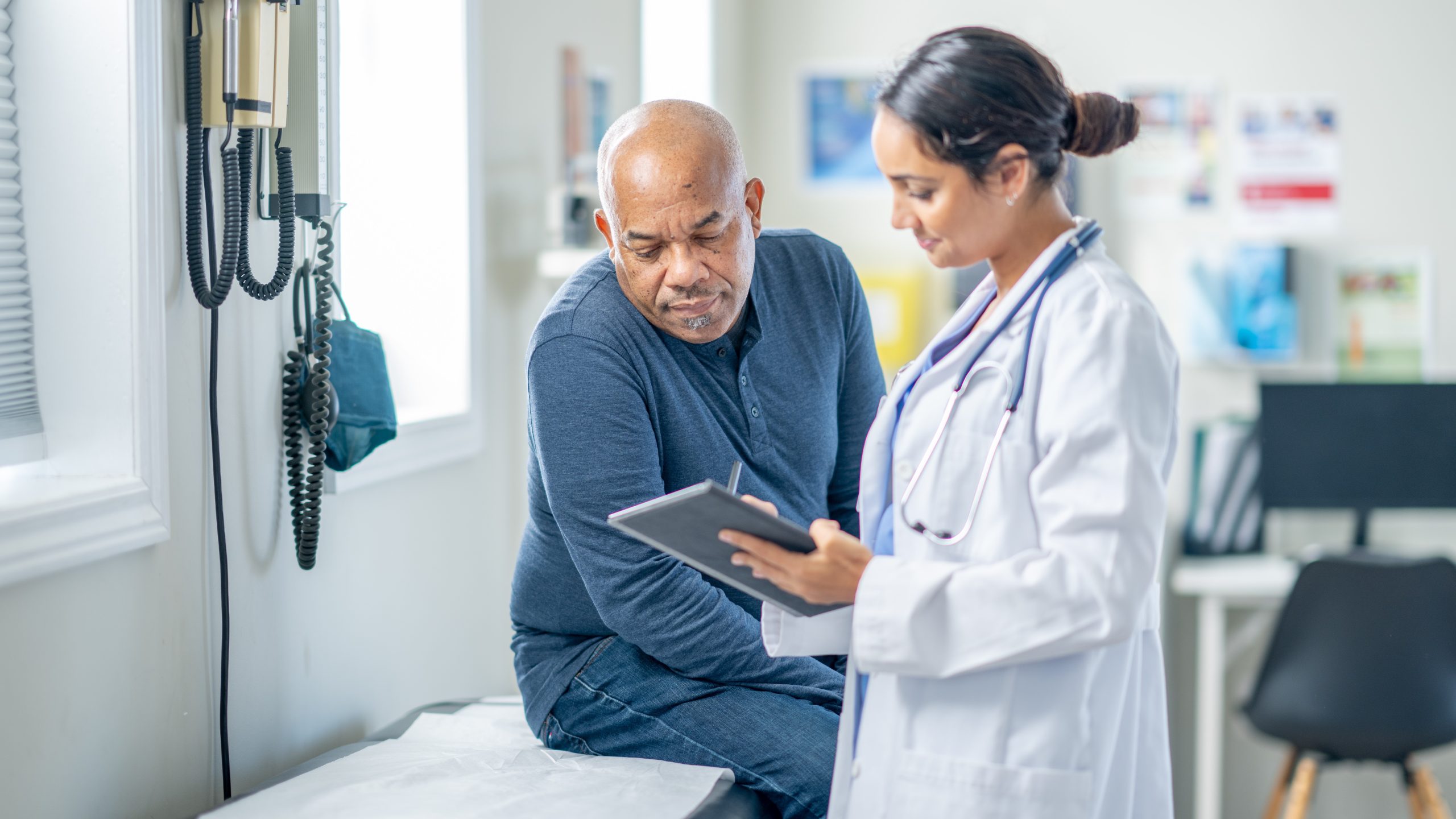 Adult wellness visit Healthcare provider and patient looking at something on a tablet during a wellness visit.