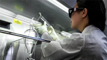 lab-test-509x339 A scientist pours liquid from one flask to another as part of wastewater testing for poliovirus.