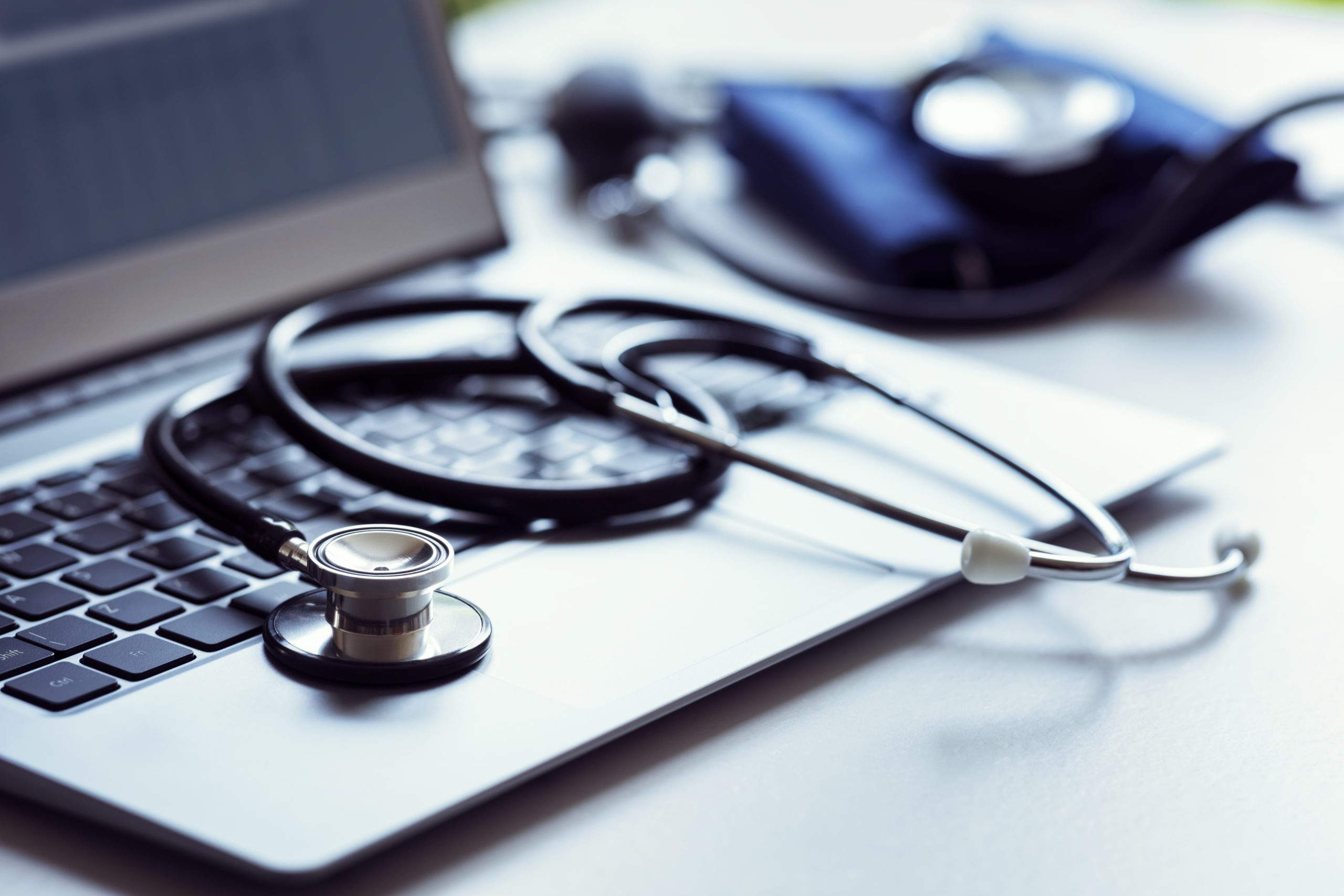 Stethoscope laying on Laptop image 258 KB A black stethoscope draped across a laptop keyboard with a blood pressure cuff laying in the background