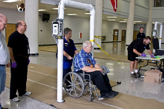 — title missing — An older man in a wheelchair being screened for radiation