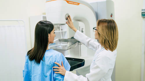 — title missing — A doctor helping a female patient prepare for a mammogram.