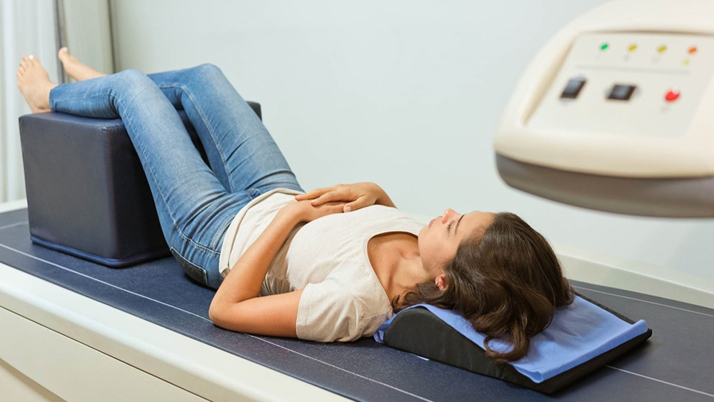 — title missing — Woman being scanned by a bone density scanner.