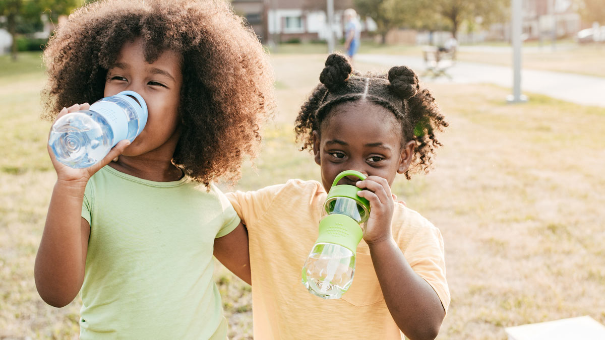 Girls drinking from water bottle Two girls at a park drinking water from their water bottles