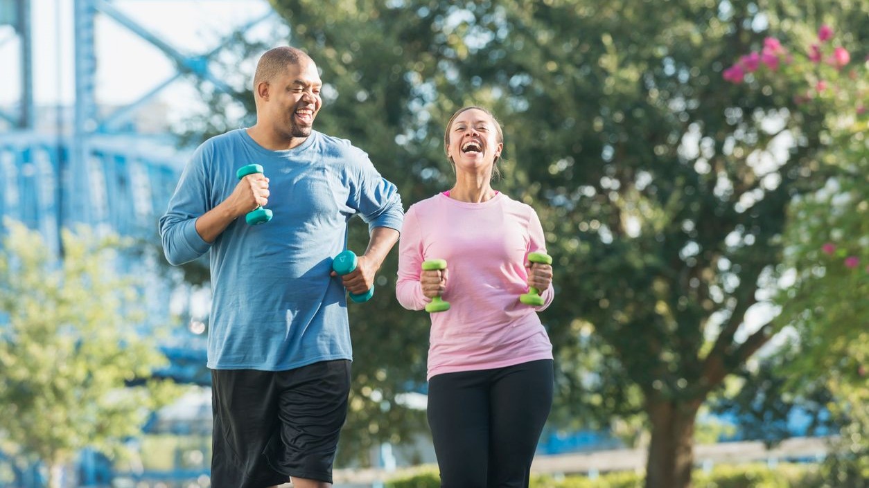 — title missing — Two people walking with hand weights in an outdoor setting