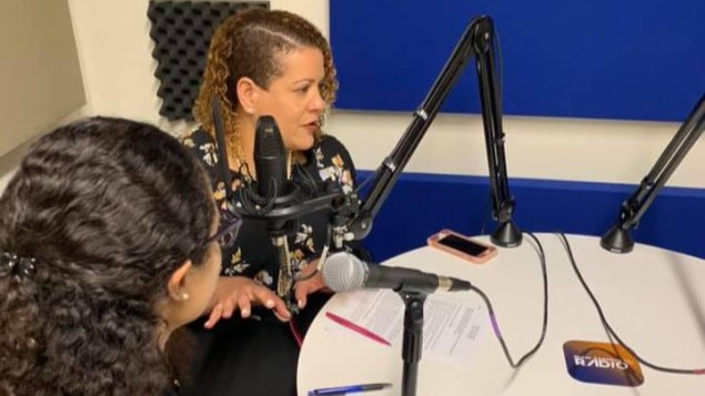 — title missing — Two people at a table with radio microphones in front of them.