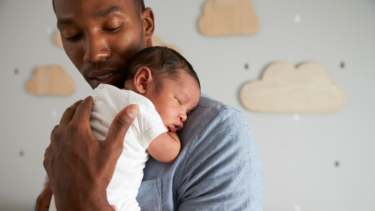 Father and infant Black young father holding newborn baby on his shoulder