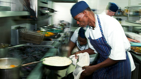 Restaurant workers Restaurant chef cooking over a stove.