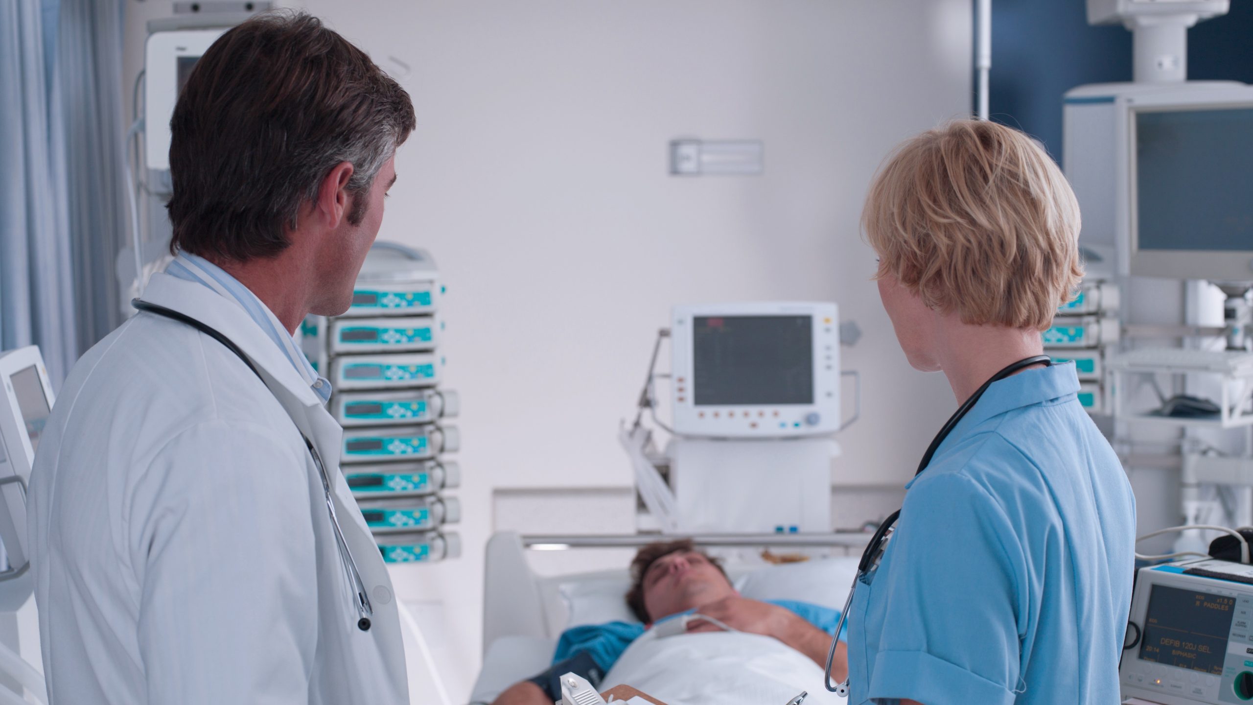 Doctor Nurse Talking ICU Doctor and nurse talking in presence of a patient lying in bed.